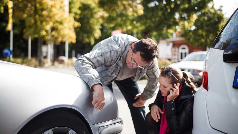Man and women examining car after accident.